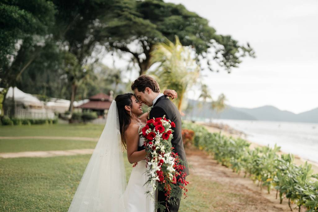 Bride in flowing white wedding gown smiles under the iconic resort pergola at Shangri-La Rasa Sayang Resort, Batu Ferringh...