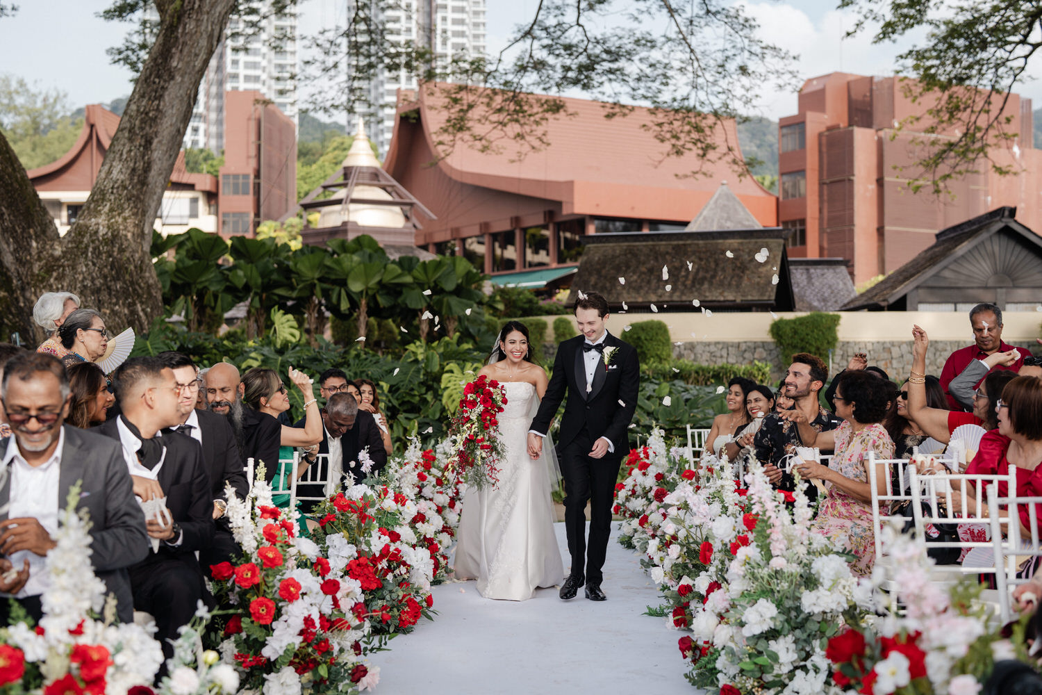 Bride in flowing white wedding gown stands framed by lush tropical greenery at Shangri-La Rasa Sayang Resort, Batu Ferring...